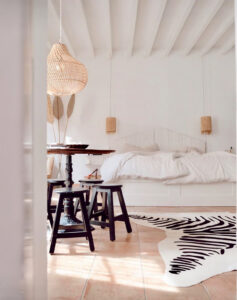 white bedroom with bed and table and hanging lamp