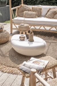 raffia stool in garden with white coffee table and rattan sofa with white cushion