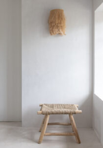 concrete wall with grass hanging lamp and sea grass stool