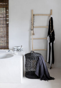 bathroom with black basket and ladder with necklages and bathrobe