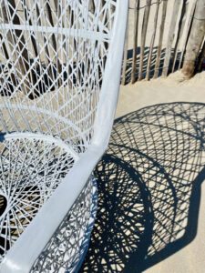 part of woven white chair with shade on beach