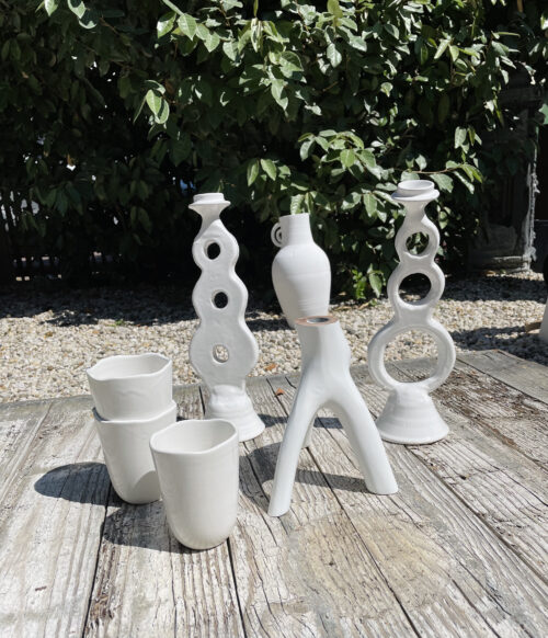 white candle holders and cups on wooden background in a garden