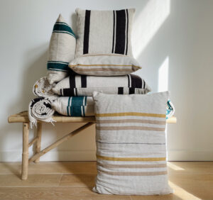 various pillows stacked on top of each other and next to each other on a bamboo bench