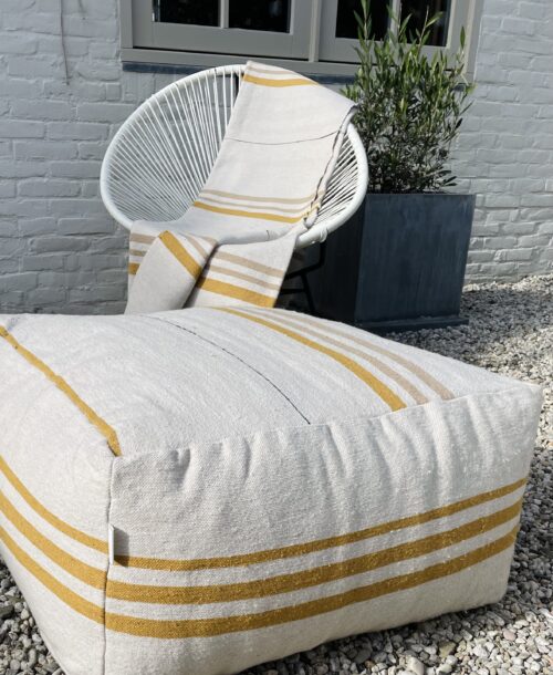 cremekleurige peof met witte stoel met daar overheen gedrapeerd een deken in de zelfde stof
